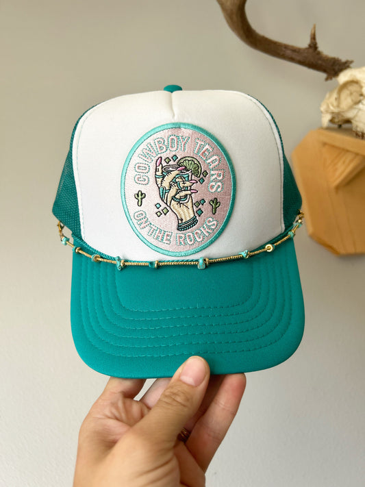 Cowboy tears on rocks with gold and turquoise hat chain